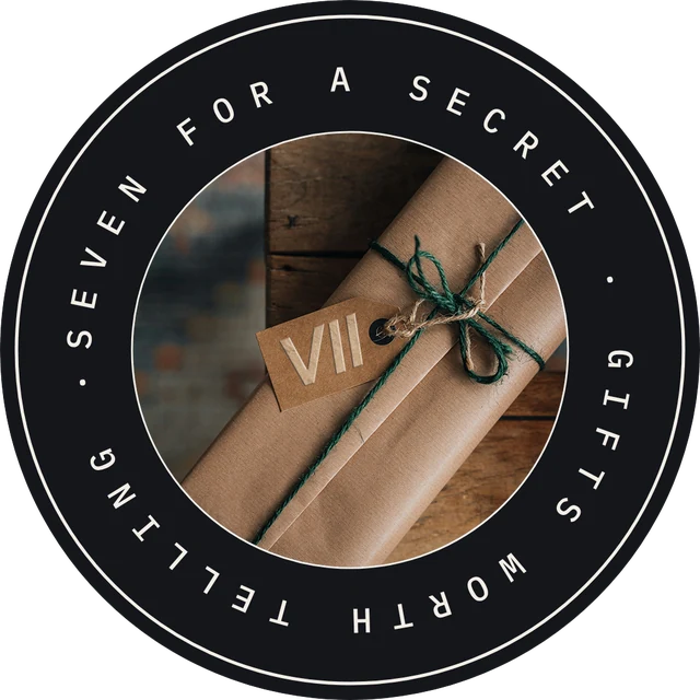 Seven for a Secret seal: a kraft-paper gift tied with green twine and a VII tag, ringed by the words Seven for a Secret, Gifts worth telling